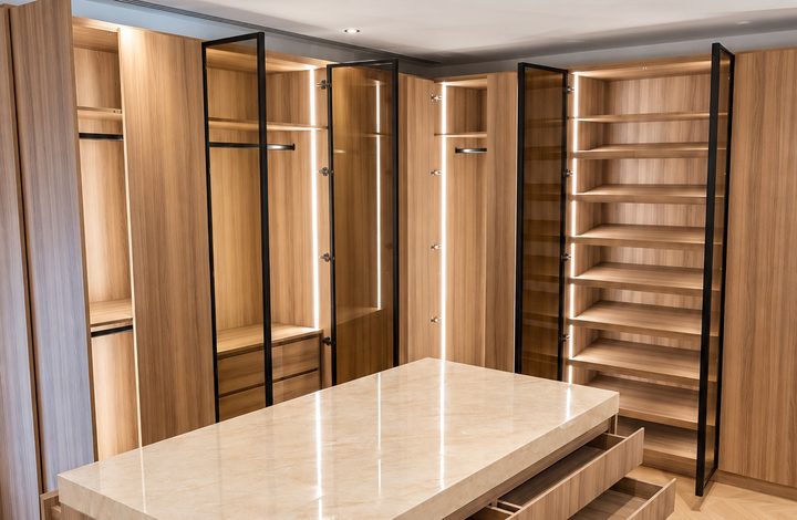 Walk-in wardrobe with open doors, drawers and lit shelving