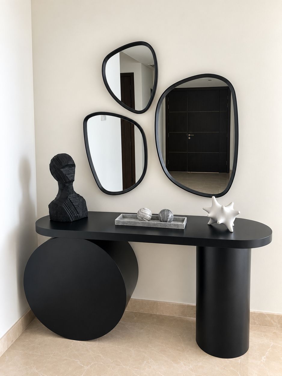 Matt black console with disc and cylinder bases beneath three mirrors